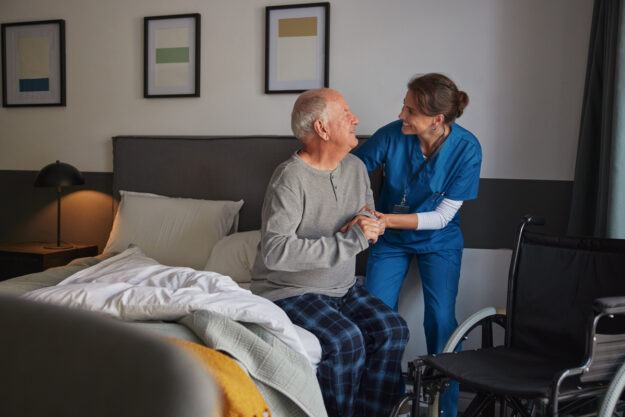 Woman helping a senior man out of bed